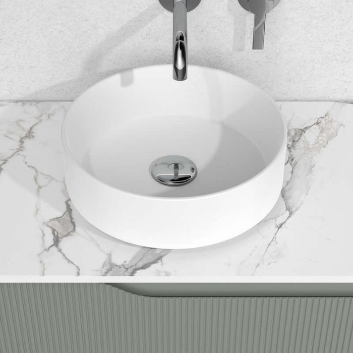 Lavabo sobre encimera modelo Unia en cerámica blanca con diseño minimalista sobre superficie de mármol.