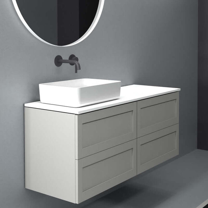Moderno lavabo sobre encimera Boren en cerámica blanca, instalado en mueble gris, con espejo redondo.