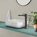 Lavabo sobre encimera modelo Leven en cerámica blanca con grifo negro en un baño moderno.