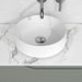 Lavabo sobre encimera modelo Unia en cerámica blanca con diseño minimalista sobre superficie de mármol.